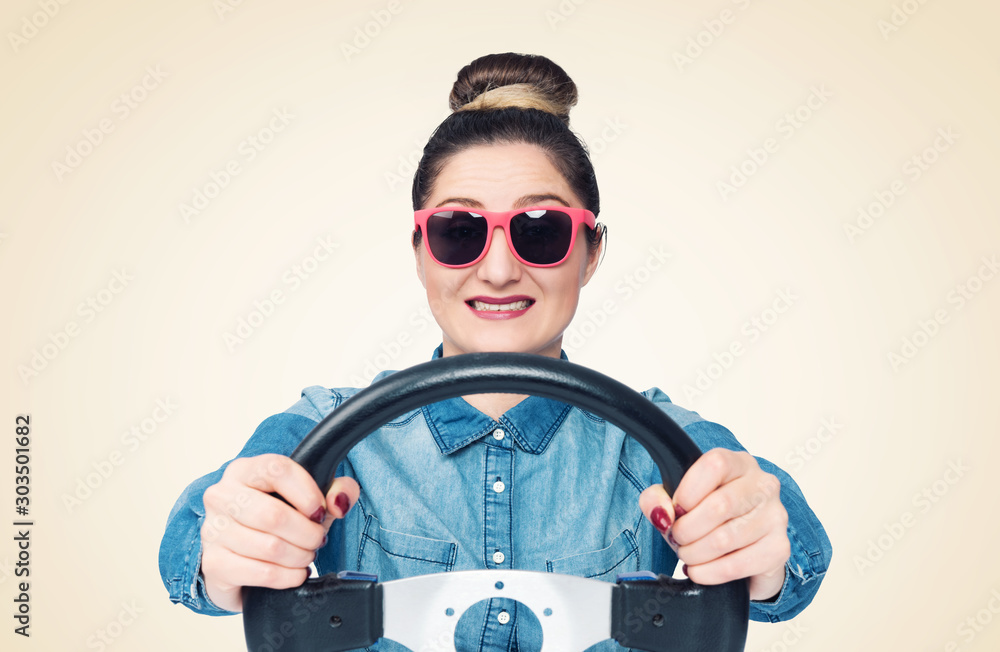 Φωτογραφία Happy young girl in sunglasses drives a car while holding a steering wheel, fron