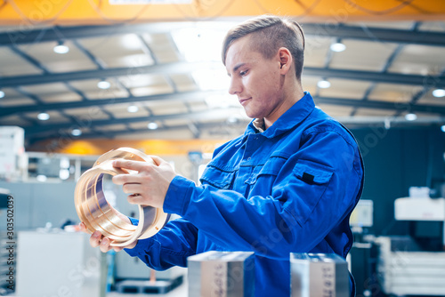 Fotografia Apprentice in metalworking looking at workpiece