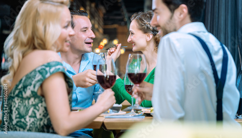 People in a restaurant eating and drinking red wine