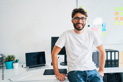 Happy photographer, web designer, young at work in office photo