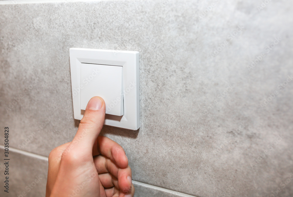 Man is switching off the lights. New sockets on the white wall. Details after renovation. Restoration process in the flat. Man is switching off the lights. New sockets on the white wall. Details after renovation. Restoration process in the flat.