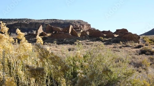 View of Pueblo Del Arroyo, part of Chaco Canyon, New Mexico, over some desert brush that is waving in the wind.  Built by the Anasazi people thousands of years ago, the ruins still stand, preserved.