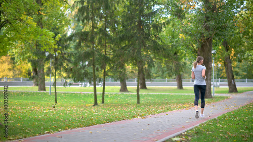 Girl athlete jogging in the park. Workout. Healthy lifestyle.