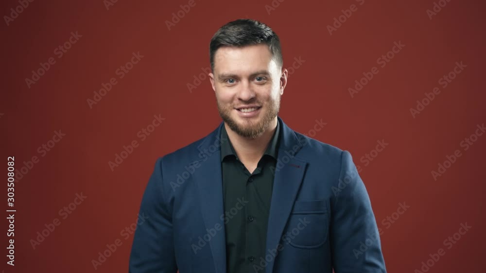 Confident businessman. Half-length portrait of brunette man isolated on claret studio. Young businessman in dark suit smiling on camera. Confident businessman. Half-length portrait of brunette man isolated on claret studio. Young businessman in dark suit smiling on camera.