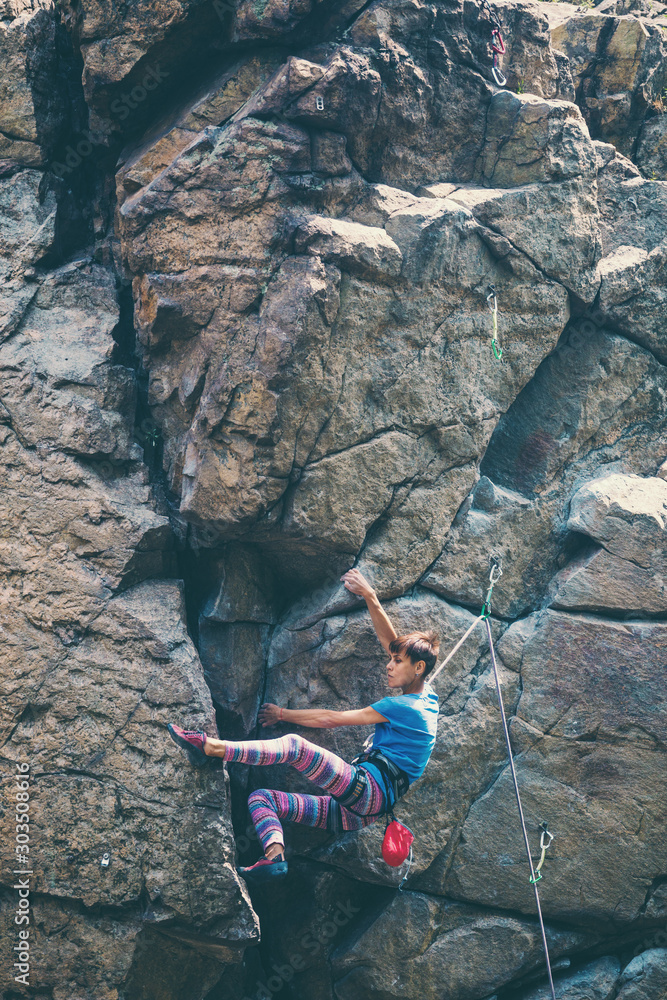 Φωτογραφία The girl climbs the granite rock.