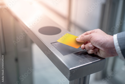 Businessman hand with business wear using yellow smart card to open automatic gate machine in office building. Working routine concept