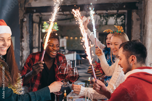 People toasting champagne celebrating with sparklers and looking at each other smiling.