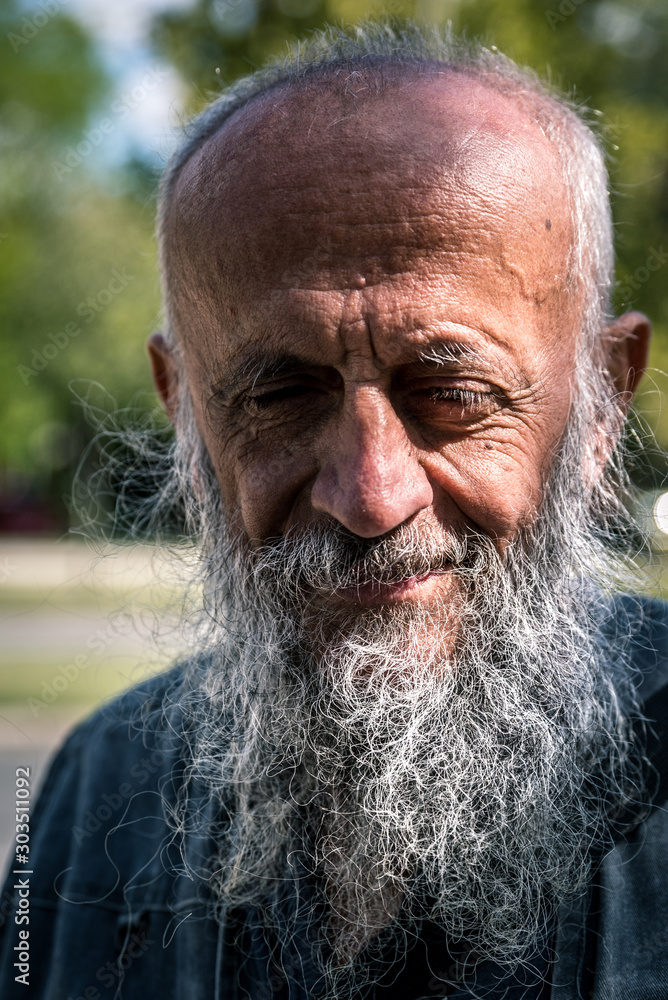 © Srdjan - Close up portrait of old smiling homeless alcoholic man face with white beard and hair wandering on the street depressed sick and lonely, social issues documentary concept