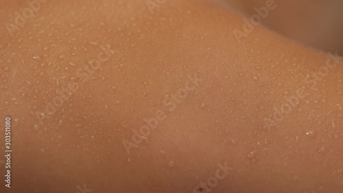 Close-up drops of sweat flowing on female body during enjoying spa sauna. A young woman lies on a couch in the sauna.