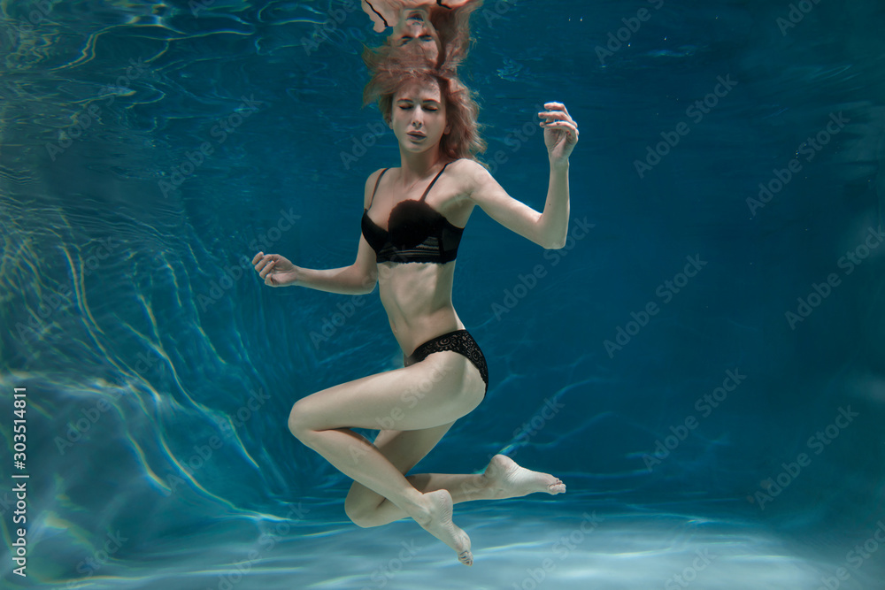 Slender beautiful girl in black underwear underwater.