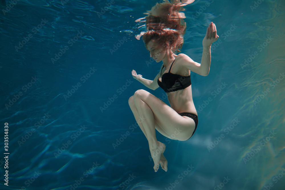 Slender beautiful girl in black underwear underwater.