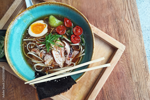 Noodle soup ramen with boiled egg on the wooden table in cafe photo