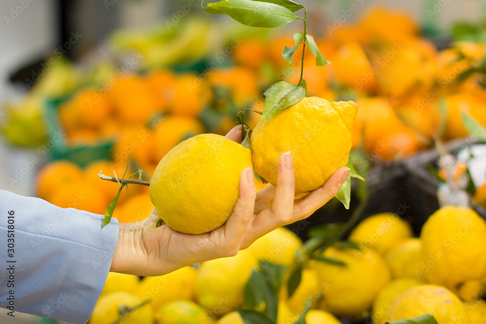 Woman hand choosing lemons at supermarket. Concept of healthy food, bio, vegetarian, diet.