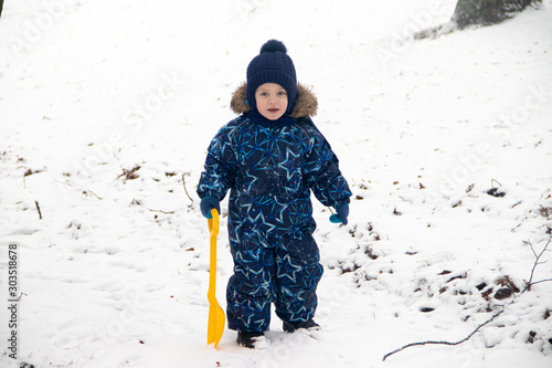 Little boy on a walk in the Park in winter. Winter park. A boy in winter overalls. Snow in the Park .