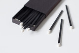Black matches in matchbox on white background