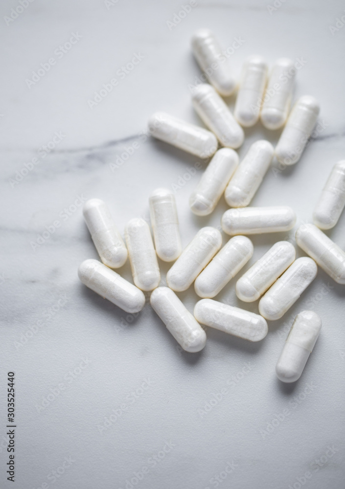 Heap Of Drugs with Glucosamine Sulphate capsules on marble background with copy space Heap Of Drugs with Glucosamine Sulphate capsules on marble background with copy space