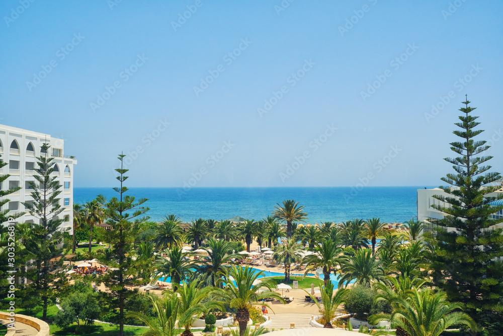 Sea view from the hotel window, copy space. Pool, palm trees and blue sky. Beautiful Arab landscape in Tunisia, Mediterranean sea.