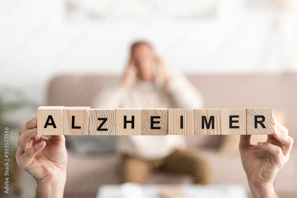 Φωτογραφία cropped view of senior woman holding wooden cubes with alzheimer letters