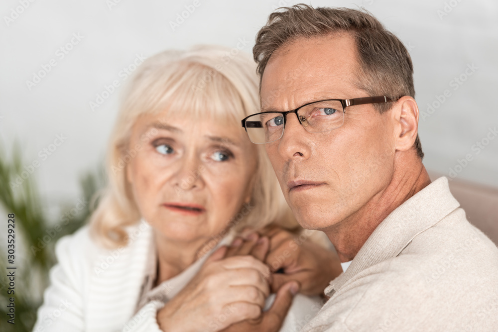 selective focus of sick senior man in glasses holding hands with wife selective focus of sick senior man in glasses holding hands with wife