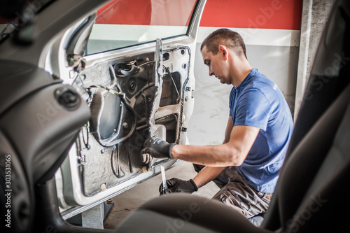 Car mechanic works on the interior of a car door