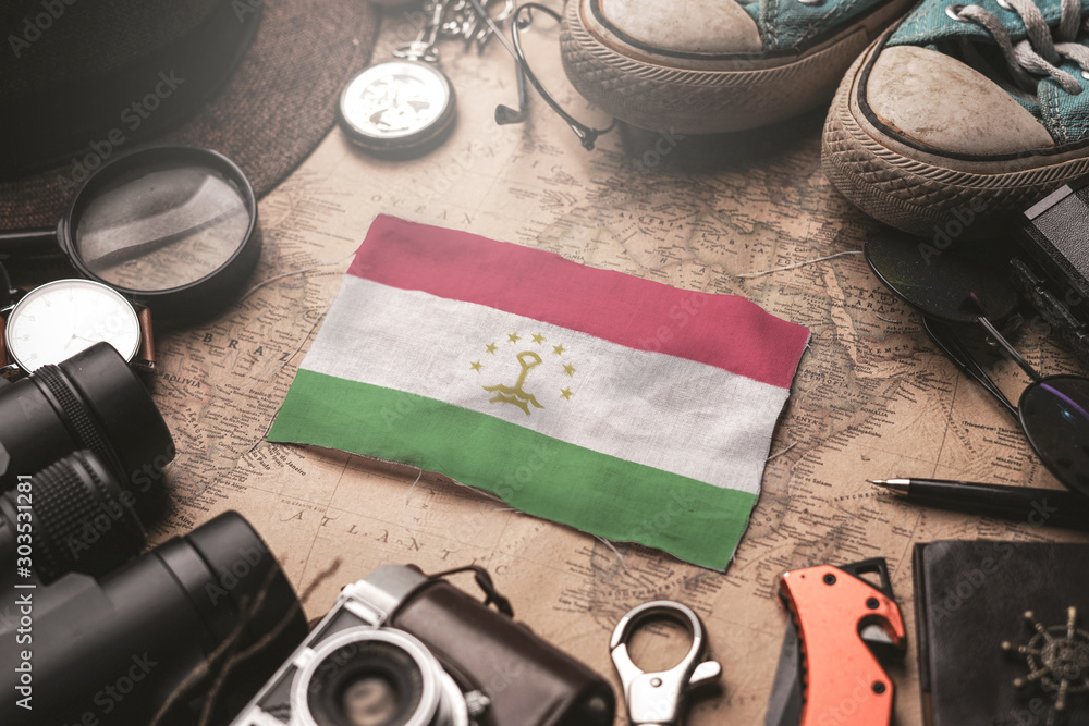 Tajikistan Flag Between Traveler's Accessories on Old Vintage Map. Tourist Destination Concept. Tajikistan Flag Between Traveler's Accessories on Old Vintage Map. Tourist Destination Concept.