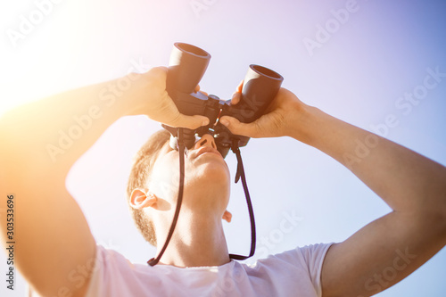 a man looks through binoculars. look through the binoculars. Close-up of a man holding binoculars in . peek. using binoculars with copyspace, binocular background concept technology