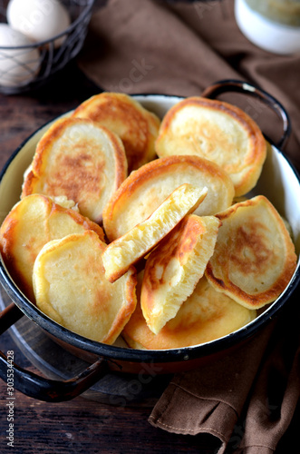 overhead breakfast shot with tasty fried russian pancakes in a bowl on a dark wooden table photo