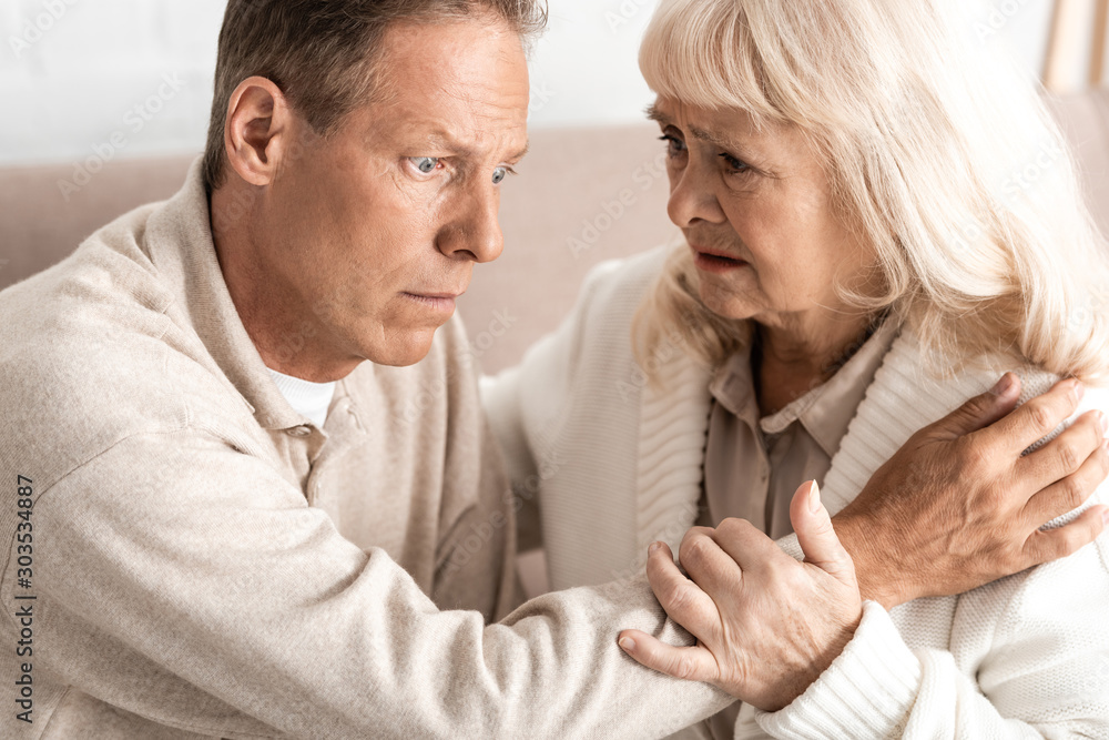 senior man with alzheimer disease sitting near worried wife senior man with alzheimer disease sitting near worried wife