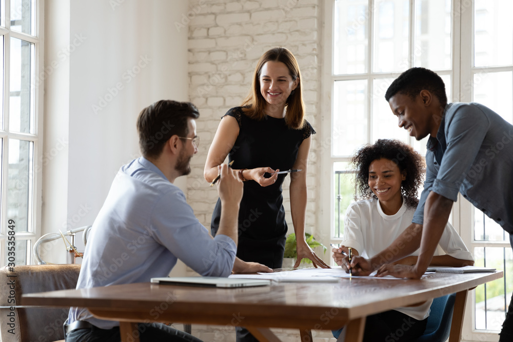 Fotografie Smiling mixed race teammates discussing projects ideas at workplace