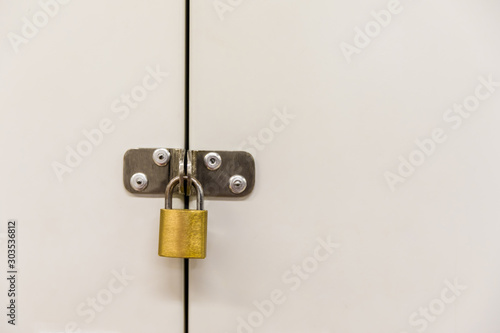 Golden padlock on white cabinet.