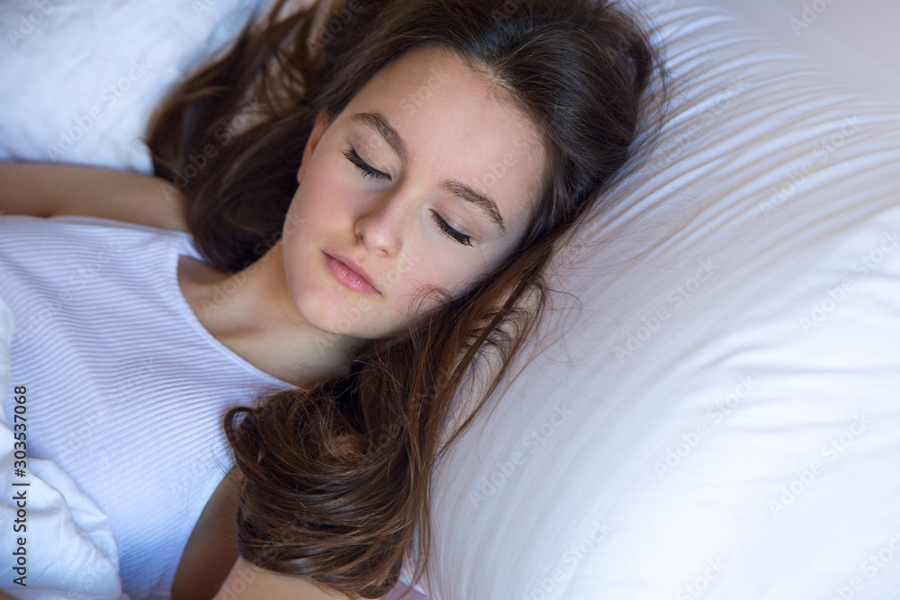 Sleeping teen girl enjoying healthy nap in cozy bed in the morning, millennial girl relaxing on soft pillow and comfortable mattress with white cotton. Sleeping teen girl enjoying healthy nap in cozy bed in the morning, millennial girl relaxing on soft pillow and comfortable mattress with white cotton.