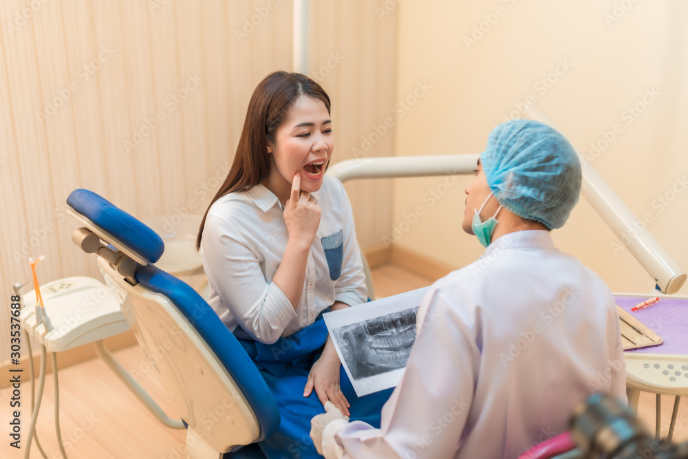 Obraz premium Asian young woman sitting in the dentist's chair with having teeth examined and consult