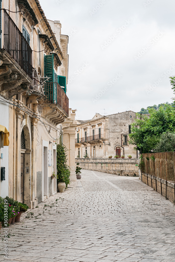 Fototapeta street with paving stones on road near buildings