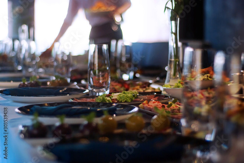 Blurred background with the image of the restaurant interior with a waiter preparing dinner dishes