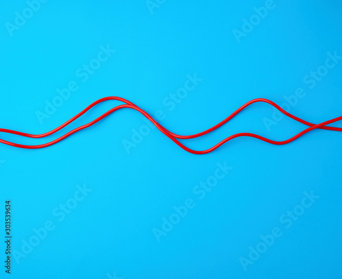 fragment of a red jump rope for sports on a blue background