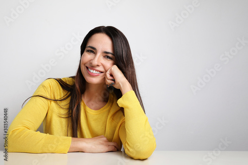 Attractive woman smiling and wearing yellow sweater posing on the white background. Isolated. photo