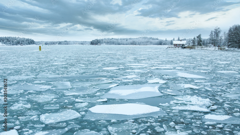 Φωτογραφία Baltic Sea with ice floes and a typical wooden house by the ice covered coast in Turku, Finland