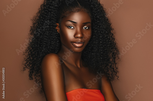African beautiful woman portrait. Brunette curly haired young model with dark...