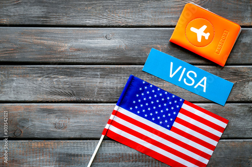 USA visa concept. American flag near passport on dark wooden background top view copy space