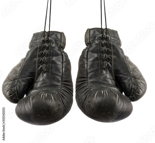 pair of very old vintage black leather boxing gloves hanging on a rope © nndanko