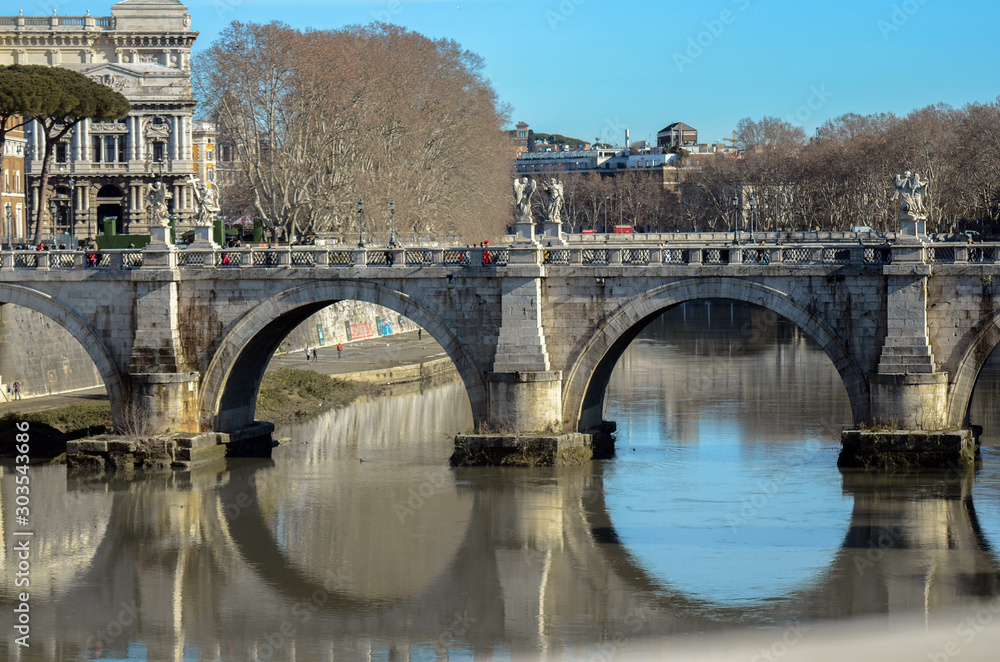 magnificent bridge with arches in Rome Italian with reflection in the water of blue sky