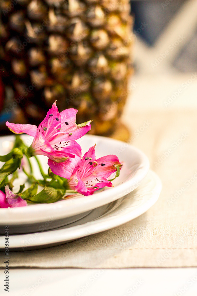 Tropical paradise heaven asian thai pink iris flower on white plate, pineapple, pomegranate on wooden tray in spa resort, restaurant. Holidays rest at sea. Food of gods. Table setting decoration Tropical paradise heaven asian thai pink iris flower on white plate, pineapple, pomegranate on wooden tray in spa resort, restaurant. Holidays rest at sea. Food of gods. Table setting decoration