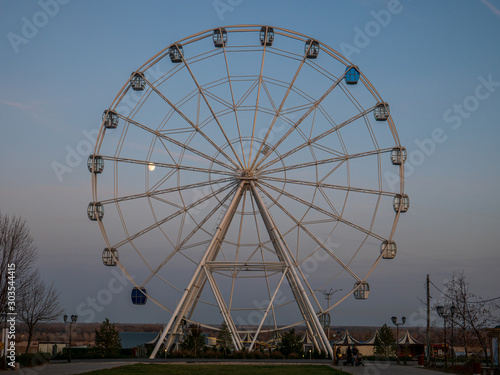 Empty cabin on Ferris wheel in leisure park are swaying in wind. Fun fair. Ferris wheel in motion with sunset in the background, people like to ride in carousel