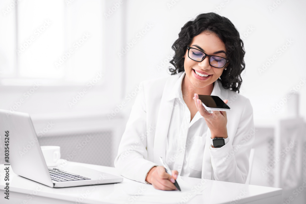 Wall Mural Happy hispanic woman using voice assistant on smartphone