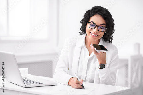 Slika na platnu Happy hispanic woman using voice assistant on smartphone
