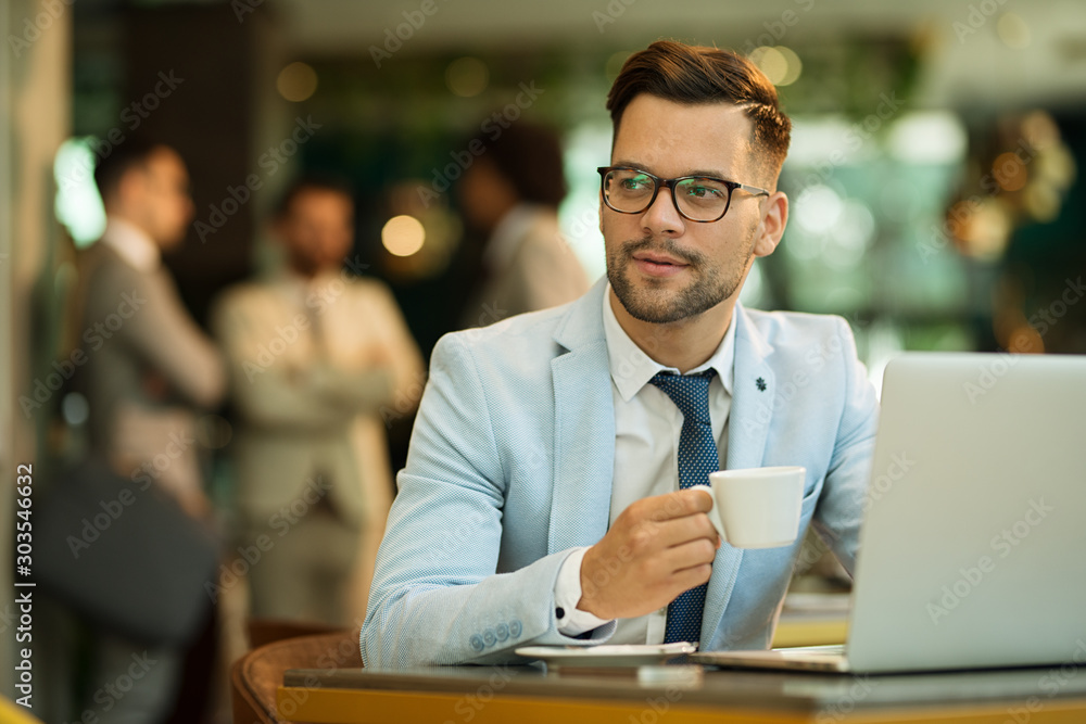 Businessman Using Laptop Whilst Working In Coffee Shop Businessman Using Laptop Whilst Working In Coffee Shop