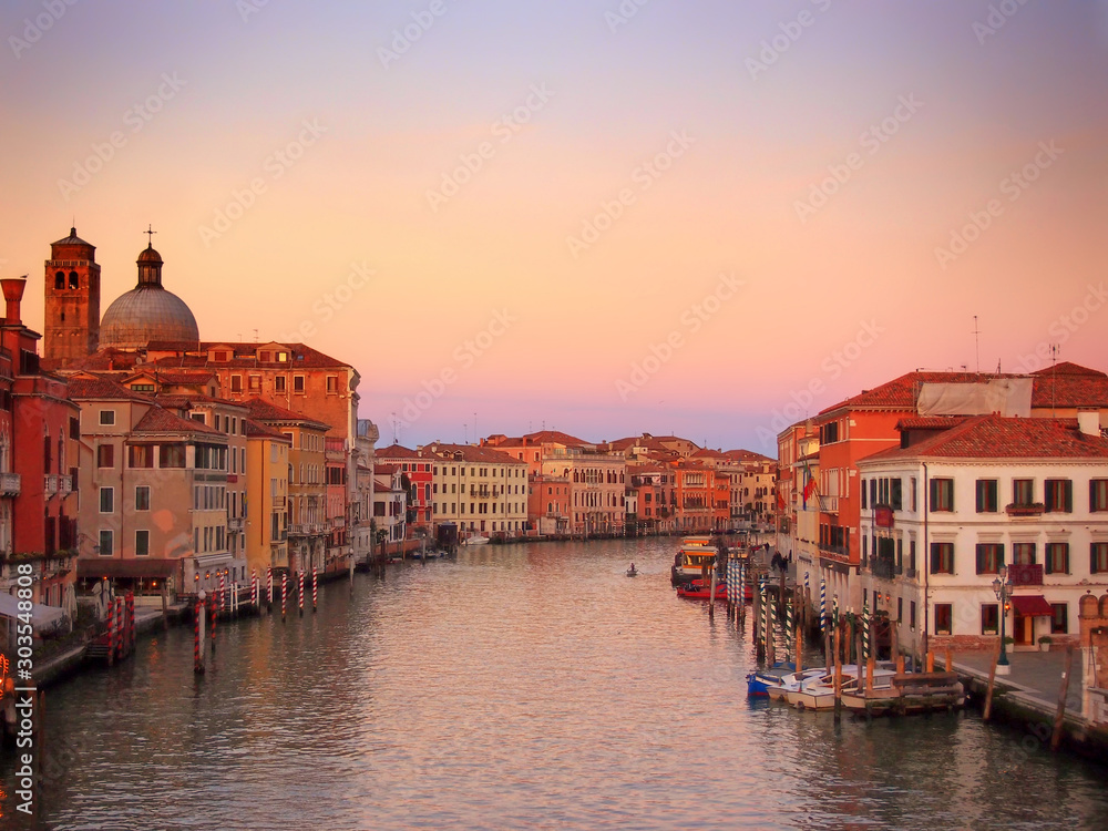 the grand canal in venice in glowing evening twilight with sunset sky with reflections of historic buildings and boats