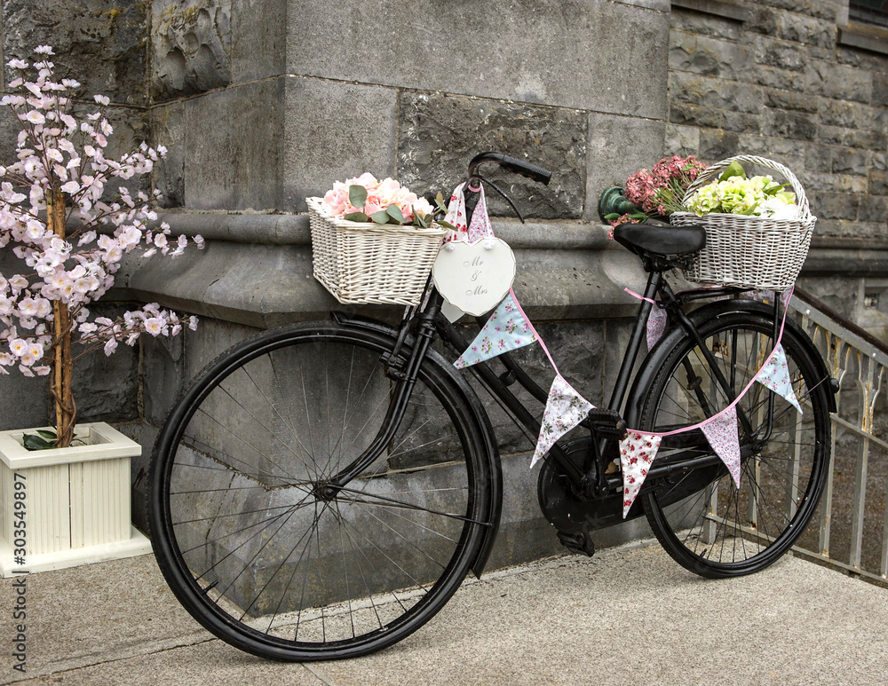 Old bicycle full of flowers outside a church for wedding
