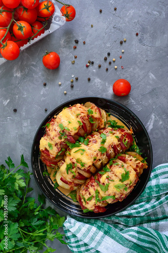 Hasselback potato stuffed with salami, cheese, ketchup, garlic and herbs. Baked whole potatoes is sliced and stuffed. Traditional swedish recipe. The top view