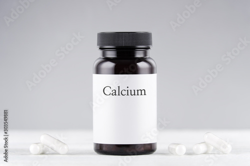 nutritional supplement calcium bottle and capsules on gray